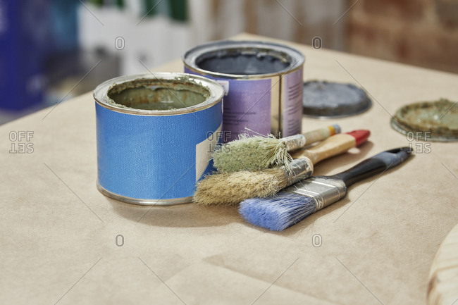 Close-up of paint cans and paintbrushes on workbench