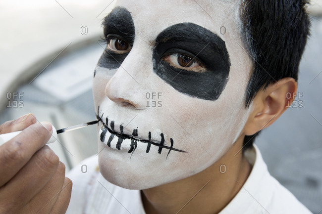 Mexico City, Mexico - November 1, 2017: Boy getting face painted for the Day of the dead celebrations