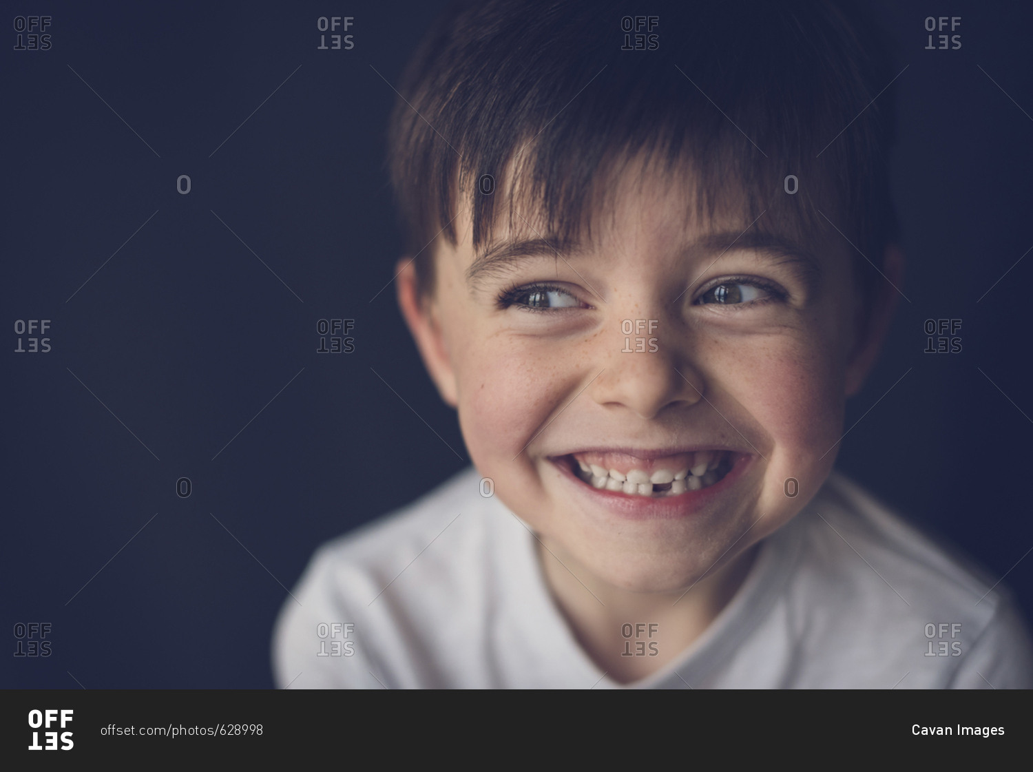 Close-up of cheerful boy clenching teeth while looking through sideways glance