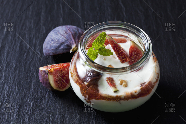 Glass of Mascarpone cream with fig compote and walnuts on slate