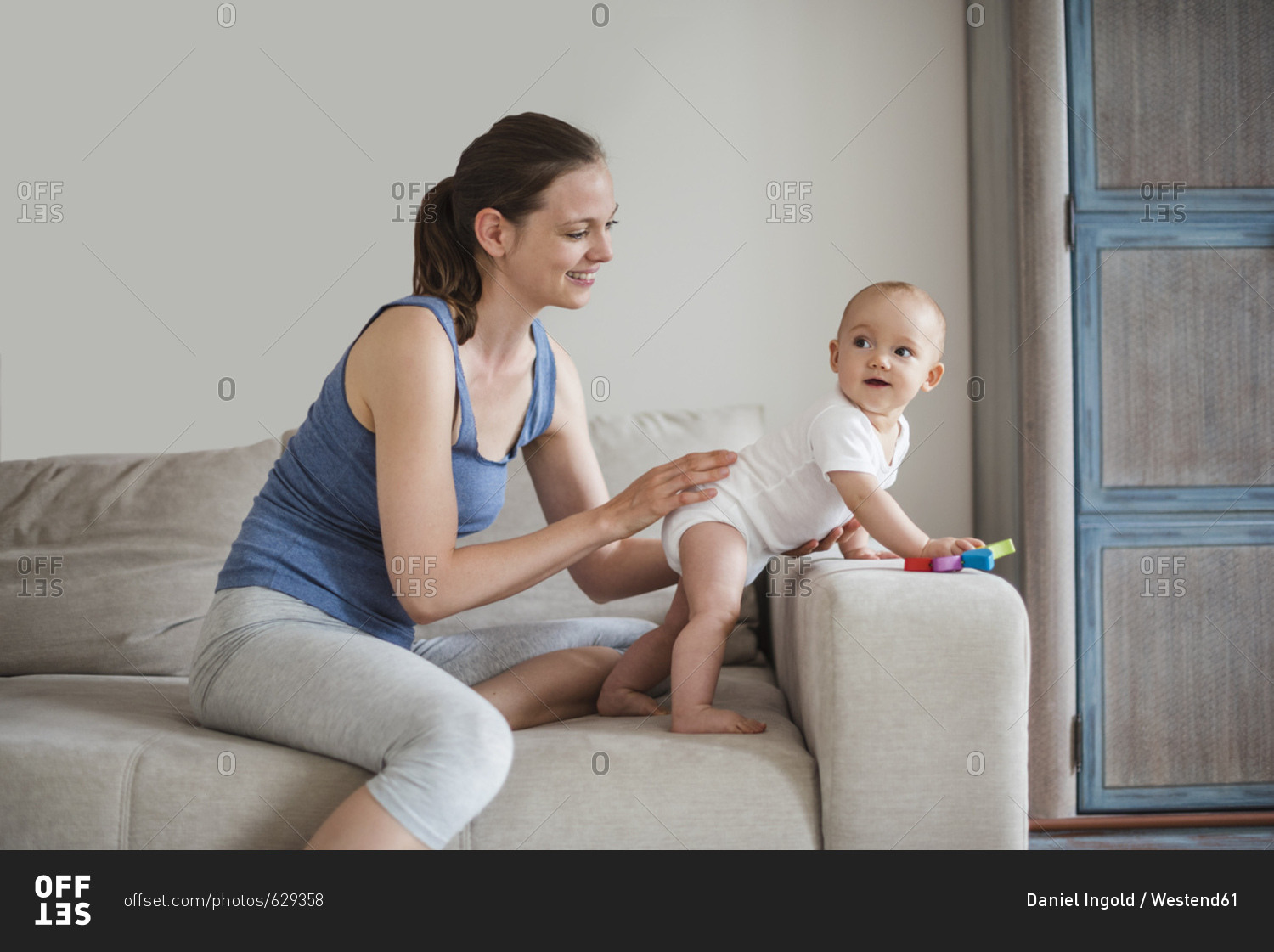 Happy baby girl with mother playing on couch