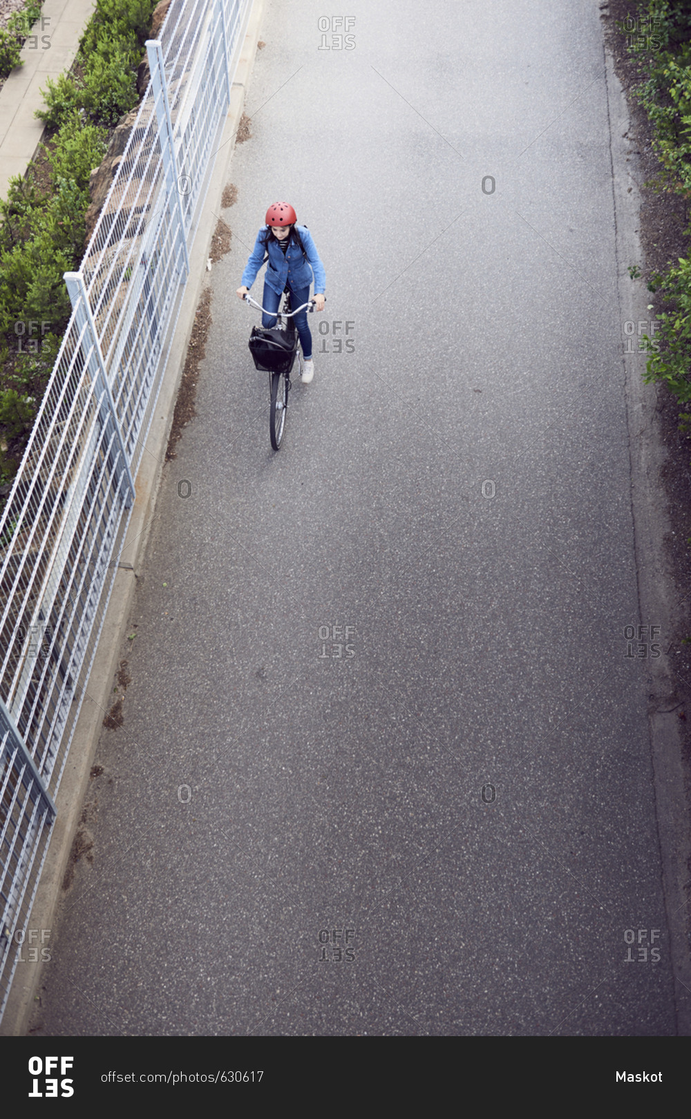 High angle view of woman cycling on road by fence