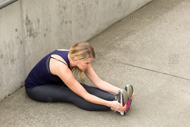 Woman sitting on ground stretching her legs before a workout