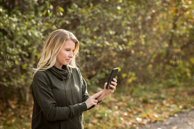 Woman checking cell phone during an autumn workout