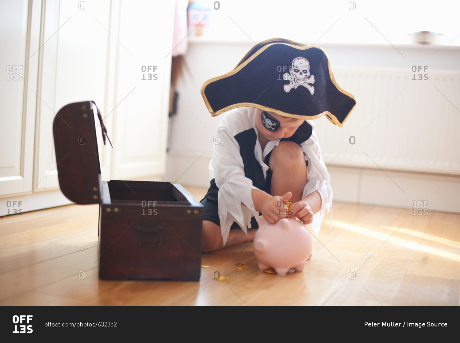 Young boy dressed as pirate, putting money into piggy bank