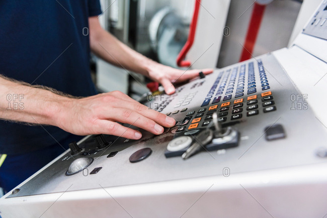 Factory worker at machine control panel in factory, mid section, close-up