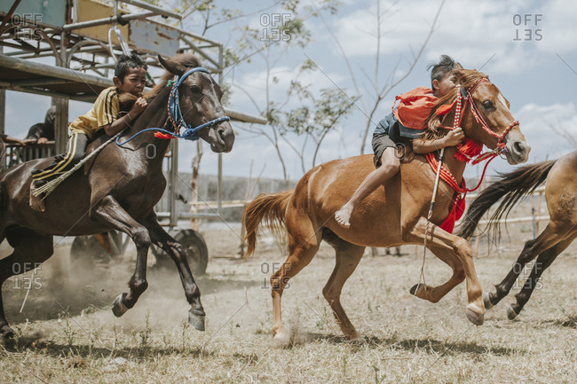 Indonesia, Sumbawa Besar - September 16, 2017: Side view of jockeys riding racehorses during horse racing