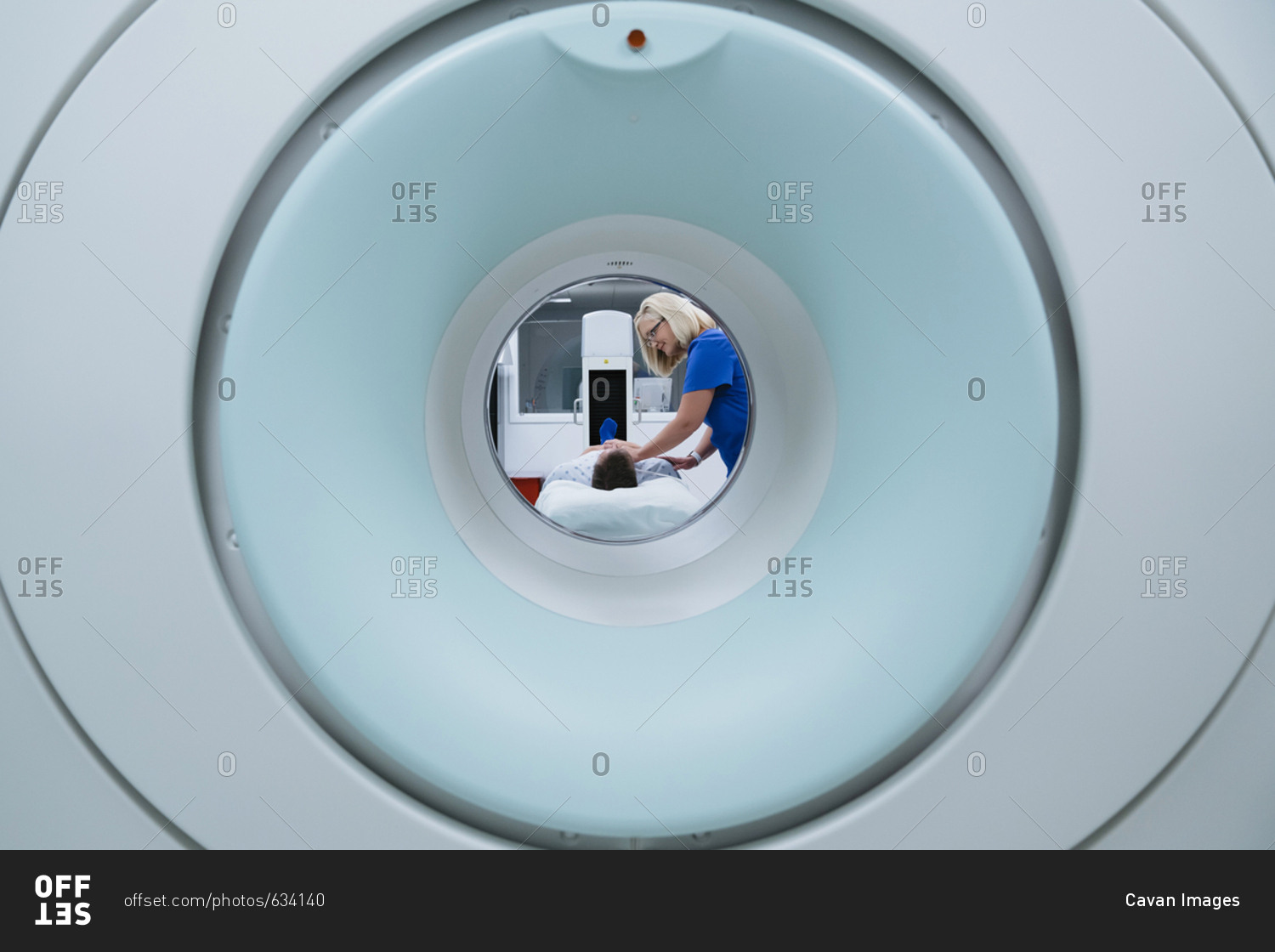 Nurse preparing patient for MRI Scan in hospital seen through scanner