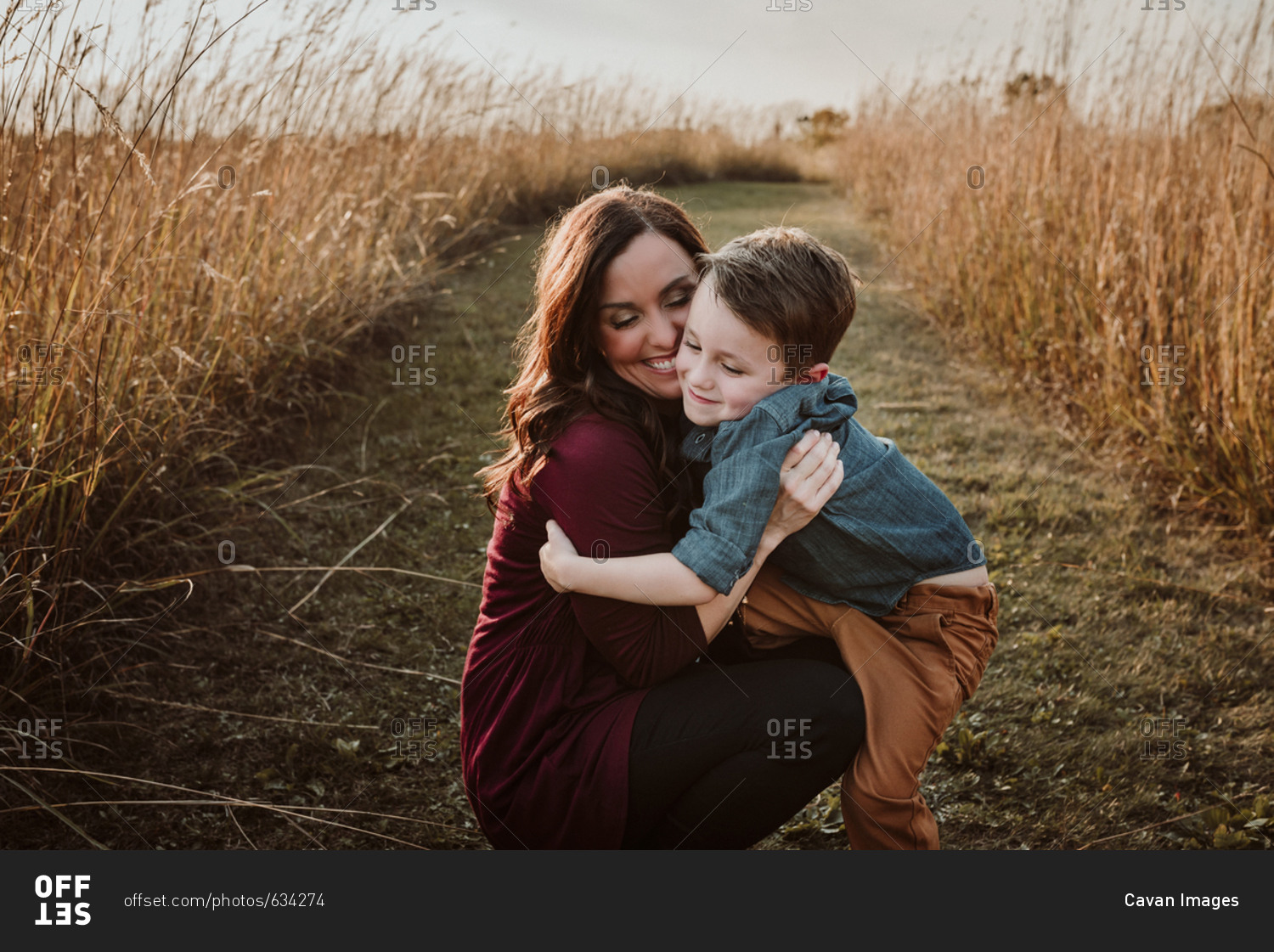 Cheerful mother with son crouching amidst field
