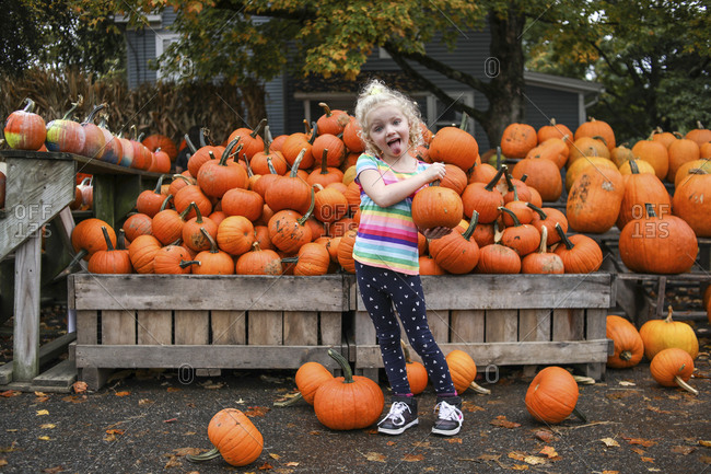 Portrait of playful girl sticking out tongue while holding pumpkin