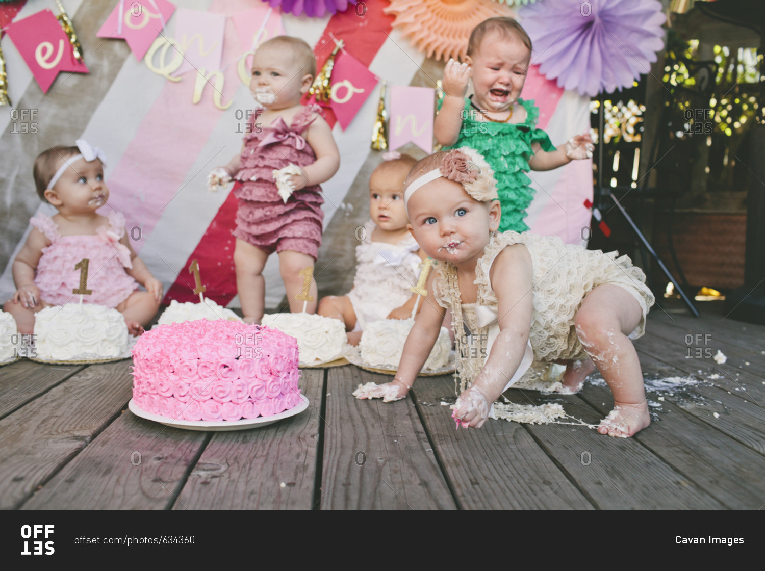 Baby girls with birthday cakes on floorboard