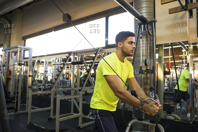 Concentrated sportsman doing chest cable flys in crossover looking forward