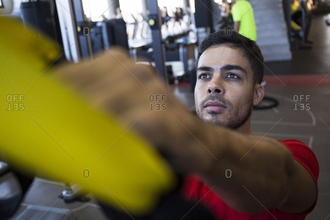 Young sportsman looking up while training suspension with special ropes in gym