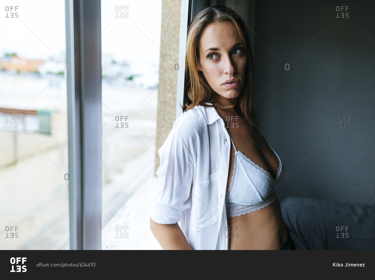 Woman looking out window with open blouse