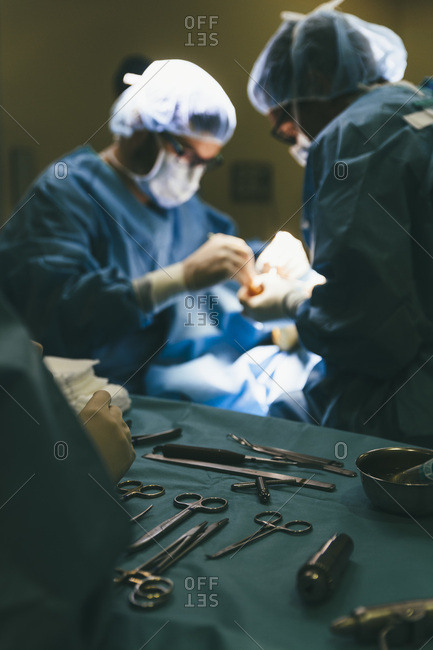 Assistant working with surgeons and providing them with instruments during operation
