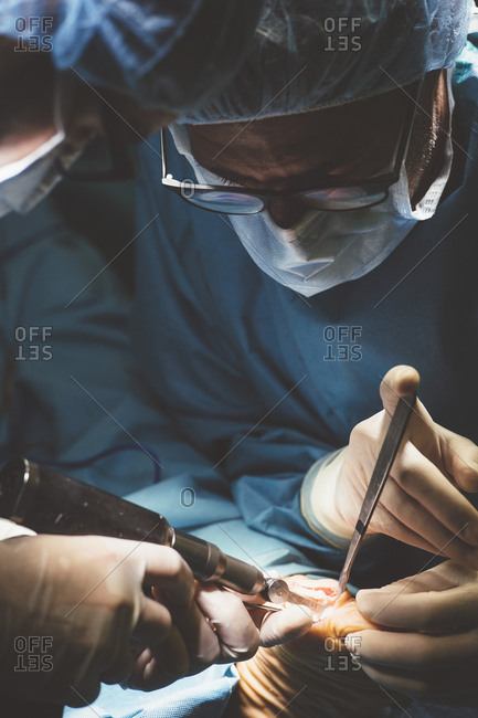Concentrated people in uniform operating patient with special instruments
