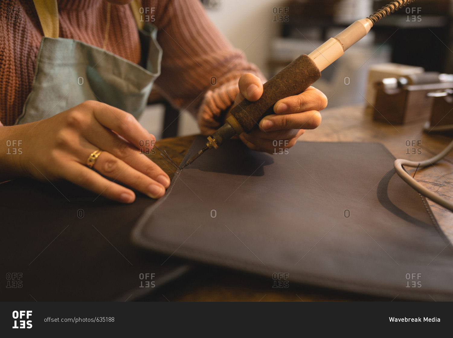 Worker stitching leather with stitching machine in workshop