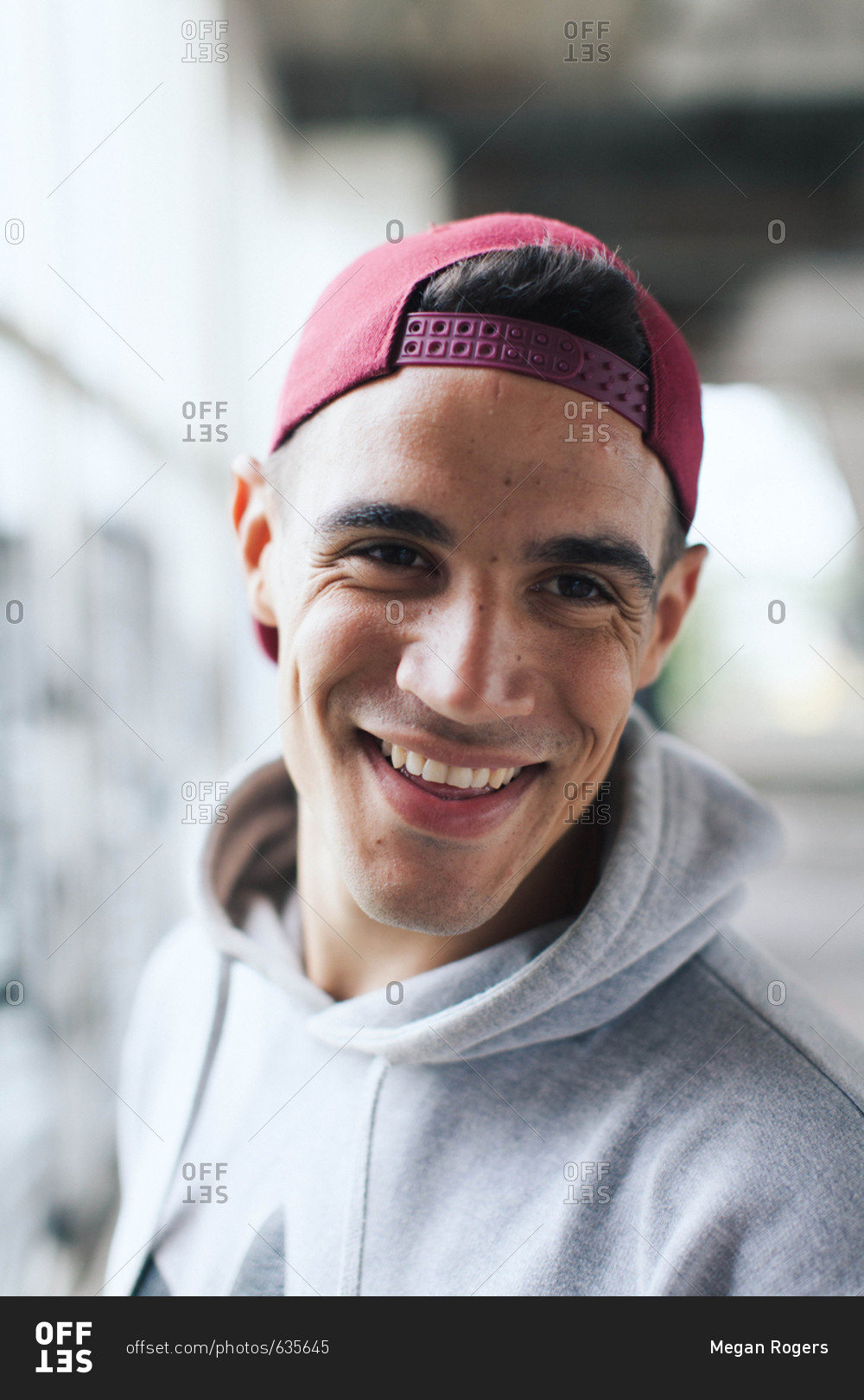 Opposite Personally lightly Portrait of trendy young man smiling in athletic wear and a backward  baseball cap stock photo - OFFSET