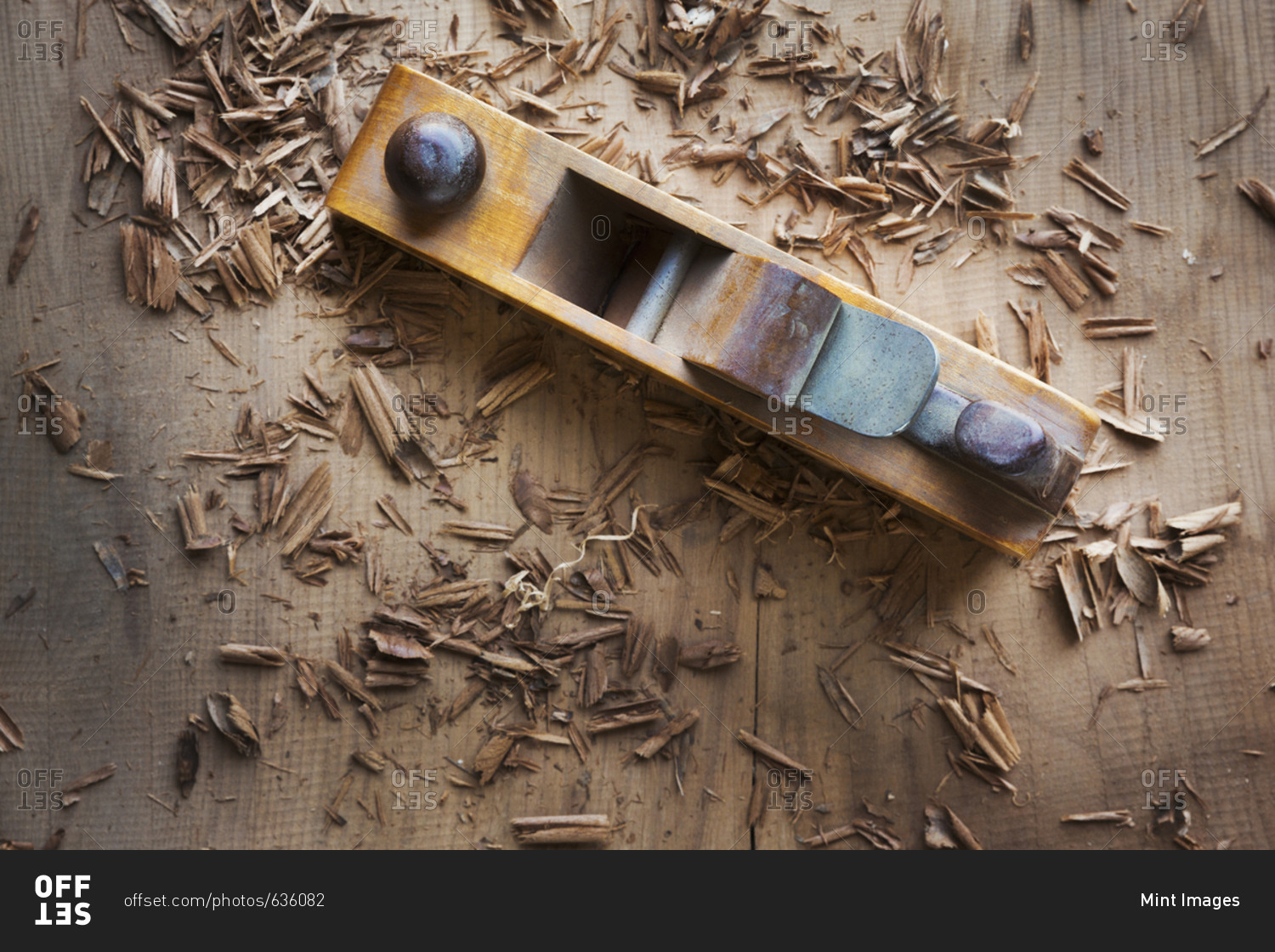 A wood plane on the surface of a piece of wood, shavings scattered about.