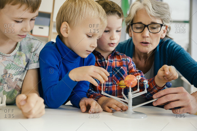 Pre School Teacher Explaining Solar System Model To Boys In