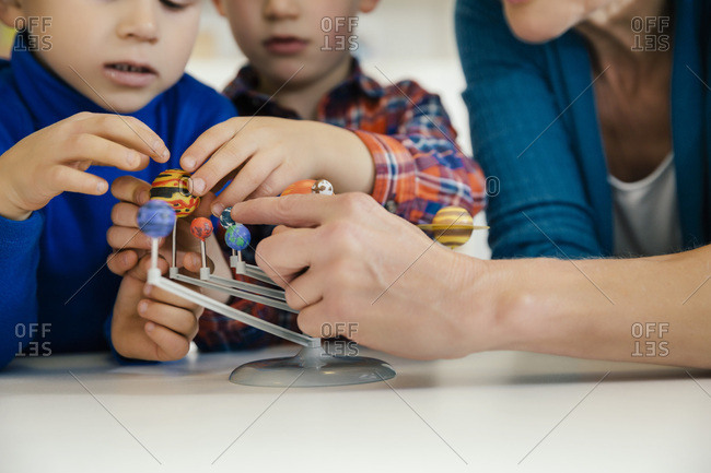 Pre-school teacher and boys exploring solar system model in kindergarten