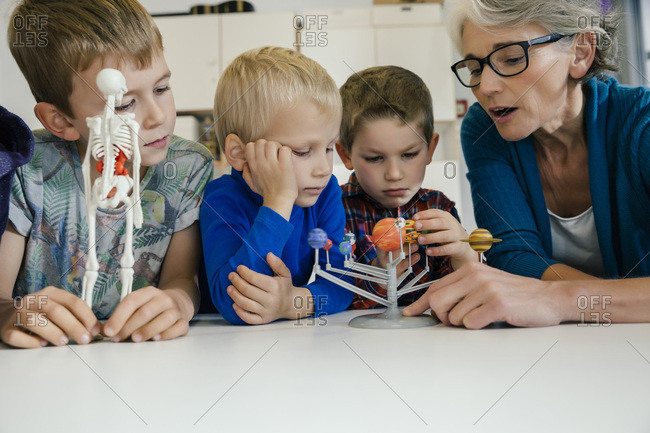 Pre-school teacher explaining solar system model to boys in kindergarten