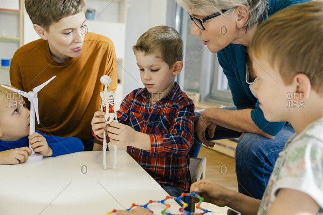 Children and pre-school teachers with wind turbine and anatomical model in kindergarten