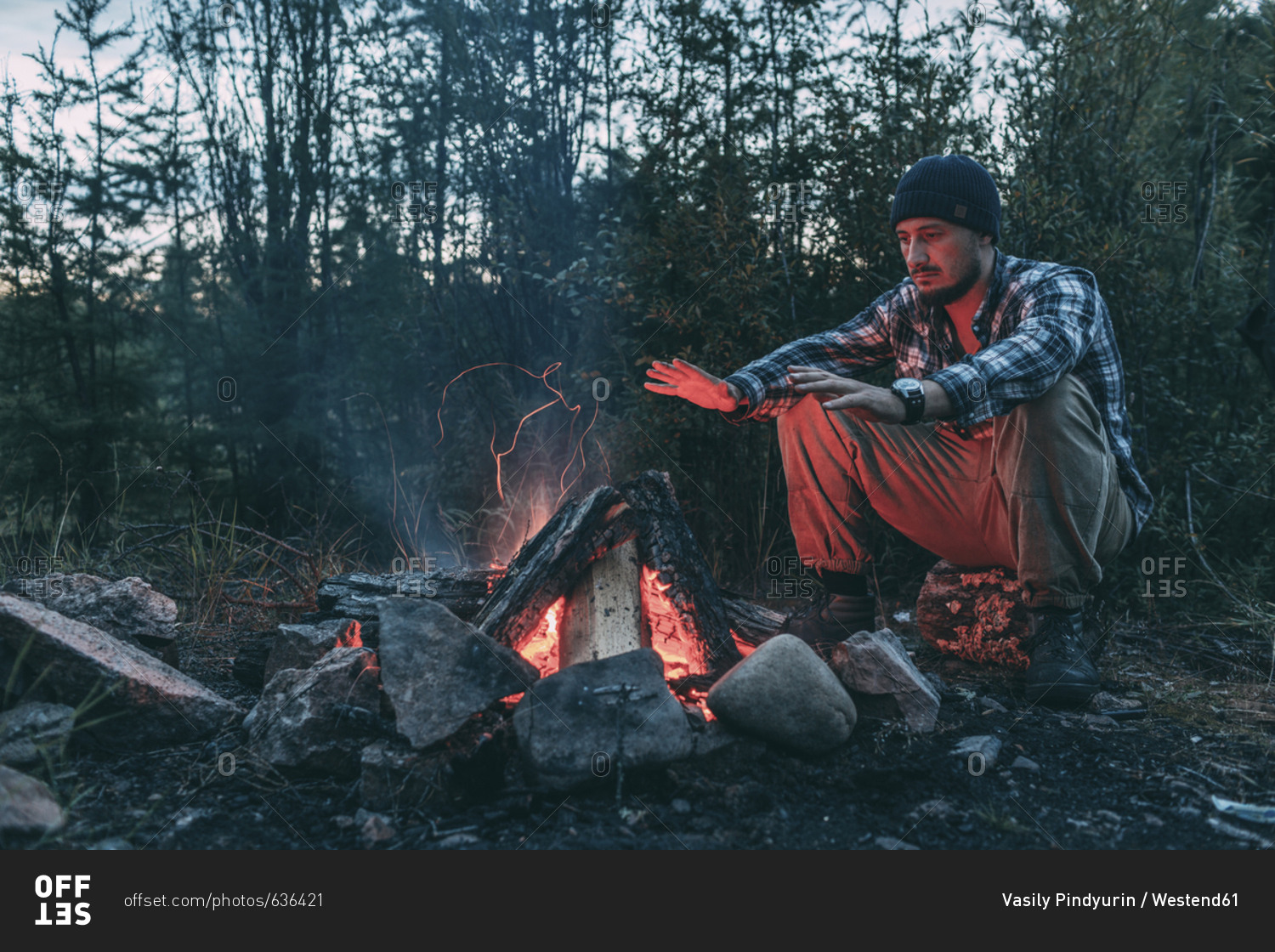 Man Sitting At Campfire In Rural Landscape Stock Photo Offset