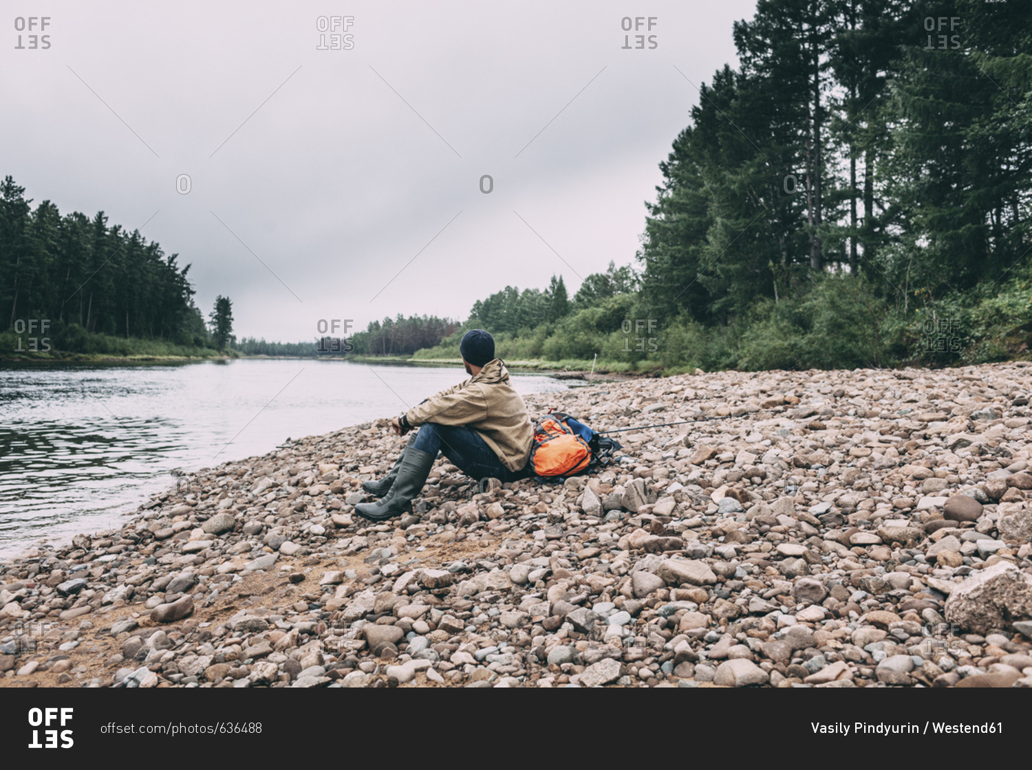 Man sitting at riverbank in rural landscape