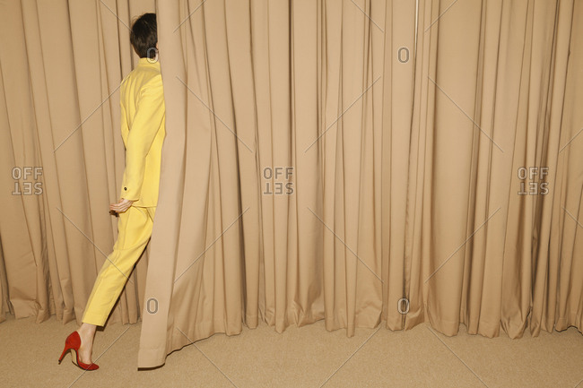 Woman with yellow suit going behind a curtain