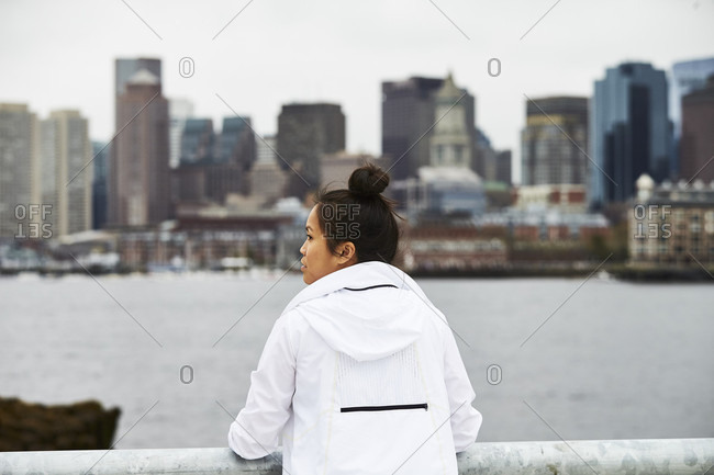 An asian woman poses for a portrait with the Boston city skyline in the background.