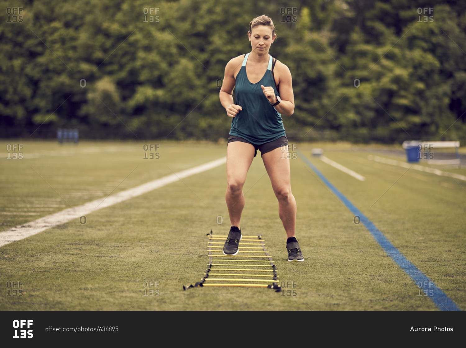 Front view of female athlete doing agility ladder exercises at athletic field, Lincoln, Massachusetts, USA