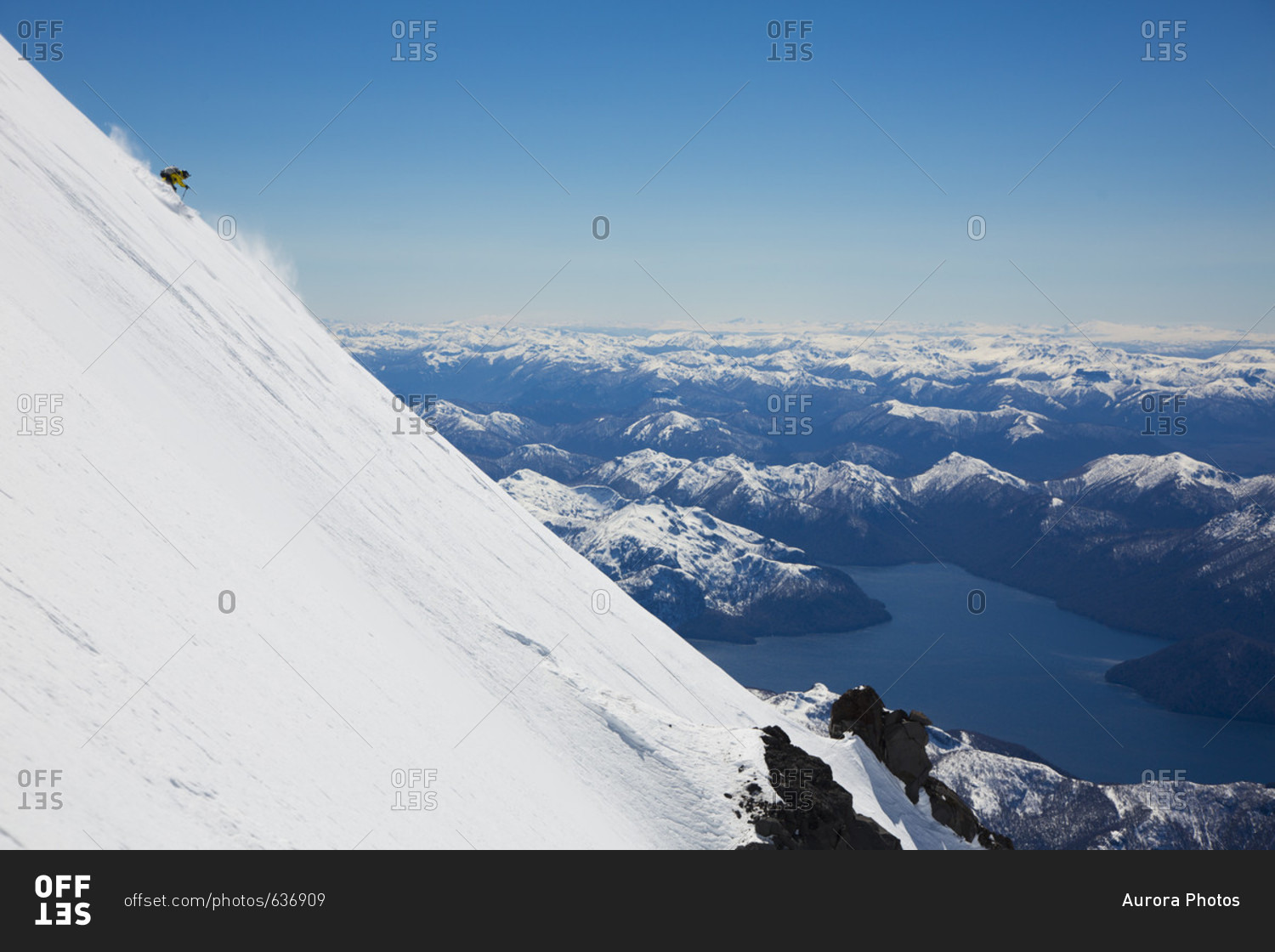 Adventurous skier skiing down steep slope with mountain range in background, Lakes District, Chile