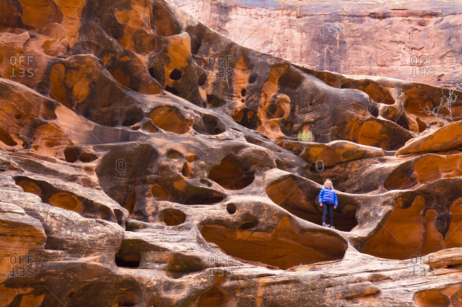 Little girl standing in eroded sandstone hole in Hunter Canyon, Moab, Utah, USA