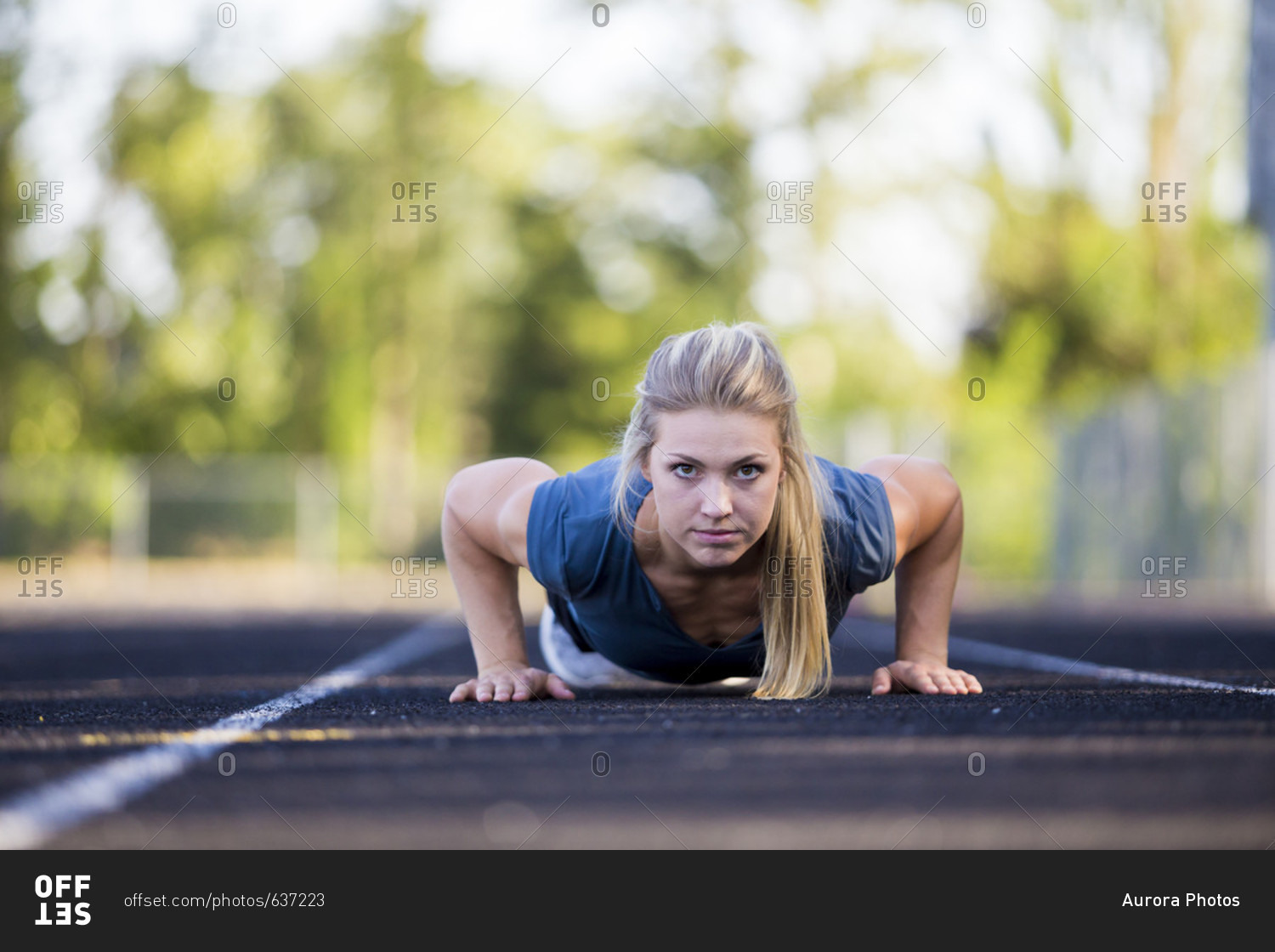 Female runner with blonde hair and ponytail exercising by doing push-ups on track, Eugene, Oregon, USA
