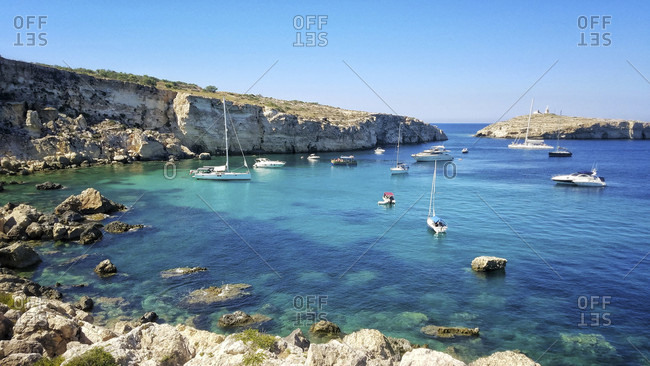 Sailboats and swimmers enjoy a quiet cove near St. Paul's Islands and the coastal town of Xemxija on Malta. This bay is famous for being the location that Saint Paul washed ashore after being shipwrecked en route to Rome. Today, the cove is a popular snorkeling and swimming destination for locals and tourists.