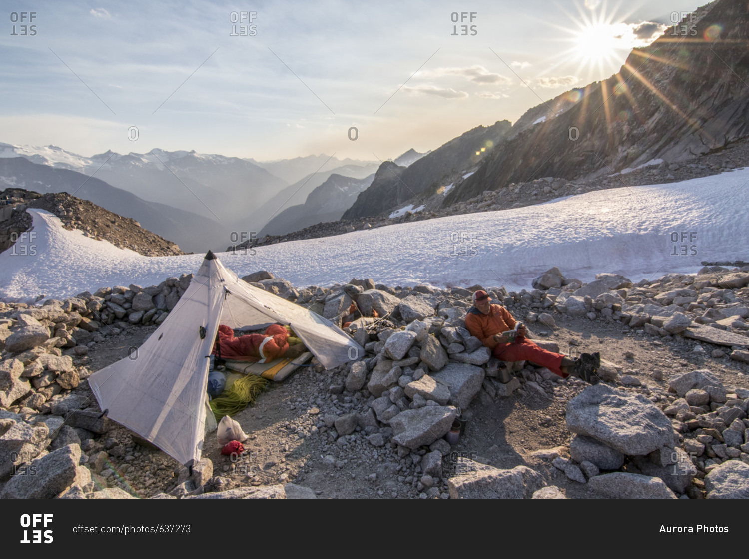 Resting mountain climber sitting near tent, East Creek Basin Bivy, Bugaboo Mountains, British Columbia, Canada