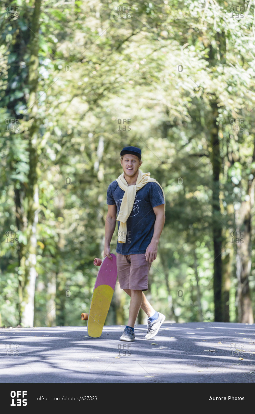 Portrait of man with skateboard standing on street, Bedugul, Bali, Indonesia