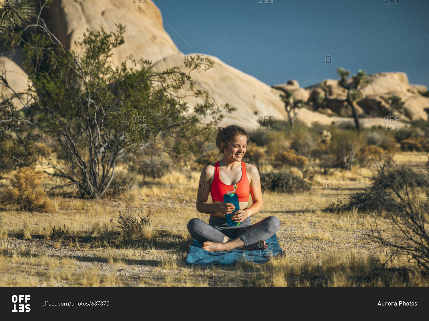 A young woman hydrates after doing yoga in Joshua Tree National Park