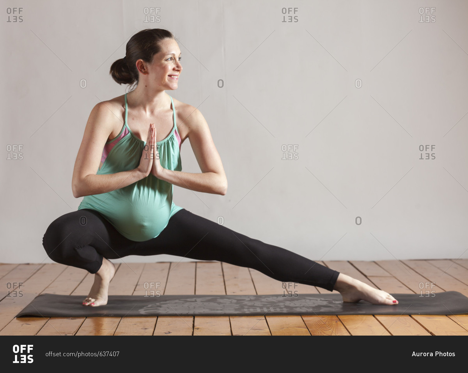 Pregnant women doing yoga pose side lunge and stretching with hands in prayer, Boston, Massachusetts, USA