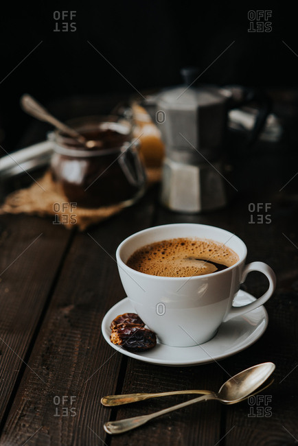 Cup of black coffee on a wooden background served with dates fruit