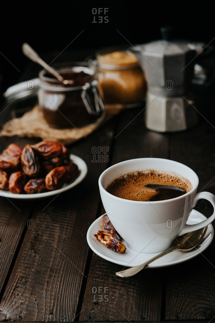 Cup of black coffee on a wooden background served with dates fruit stock  photo - OFFSET