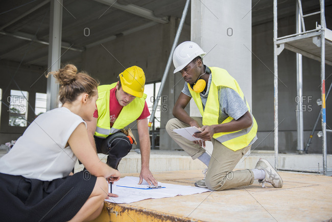 Architect discussing blueprint with construction workers at building site