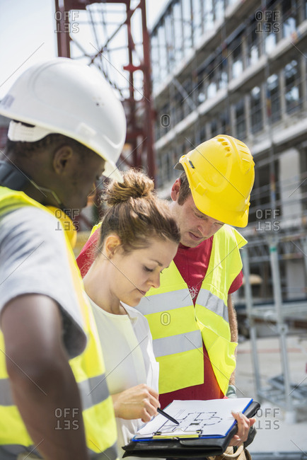 Architect reviewing blueprint with construction workers at building site