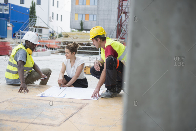 Architect reviewing blueprint with construction workers at building site