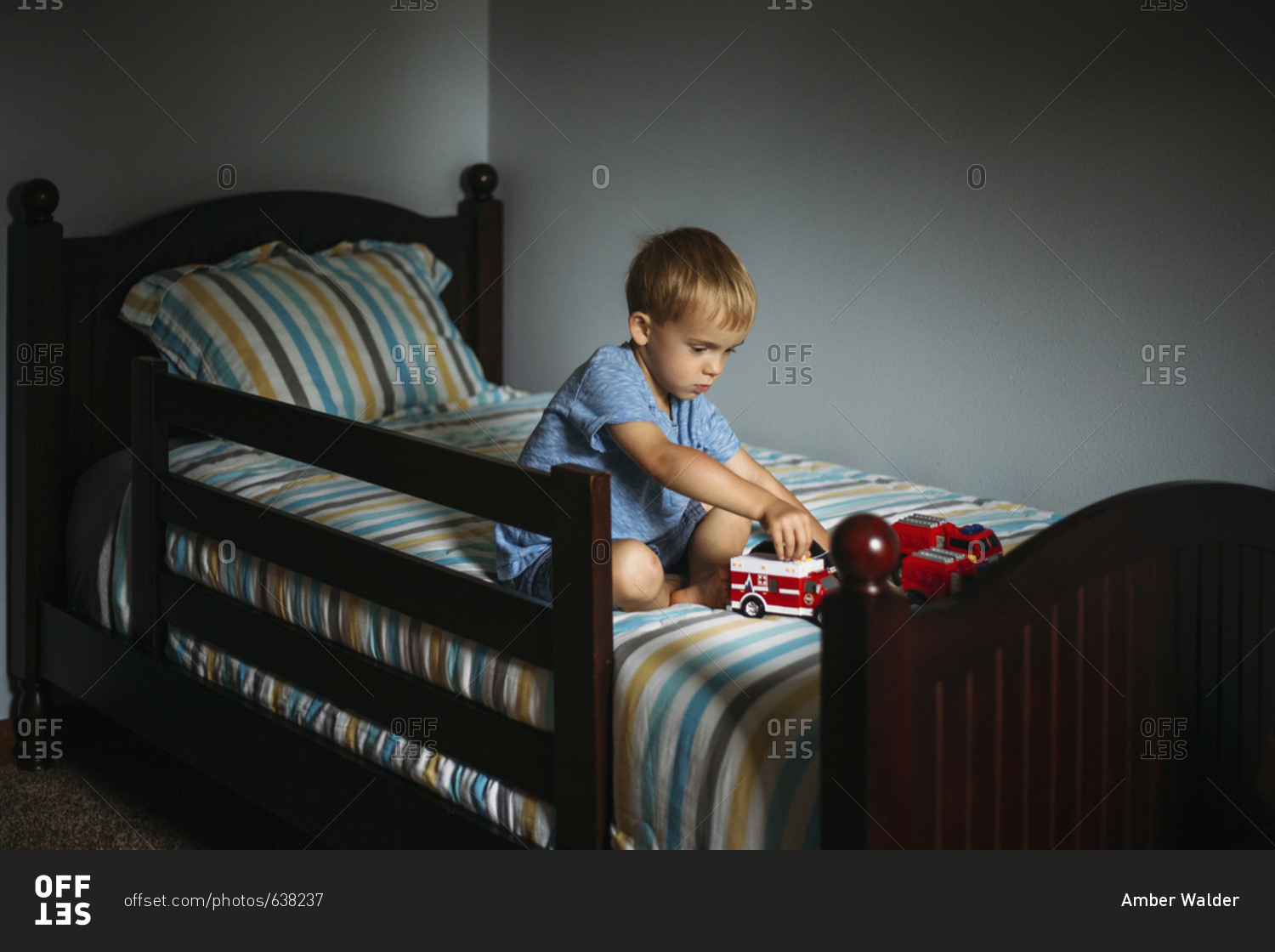 Little boy sitting in bed playing with trucks