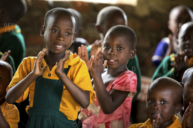 Children clapping hands while standing in classroom
