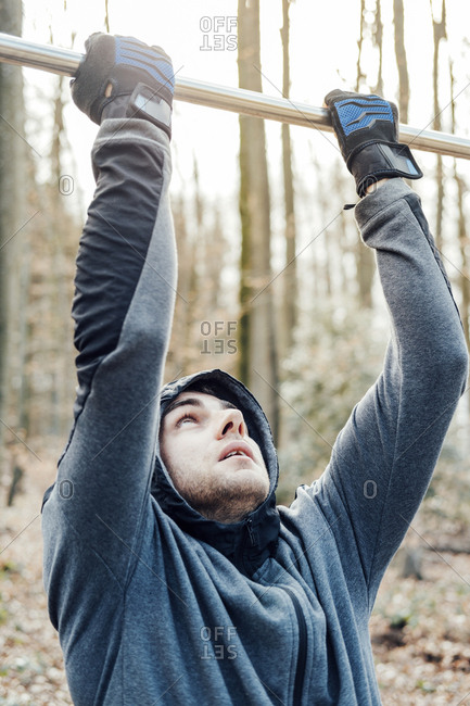 Confident man hanging on pole in forest