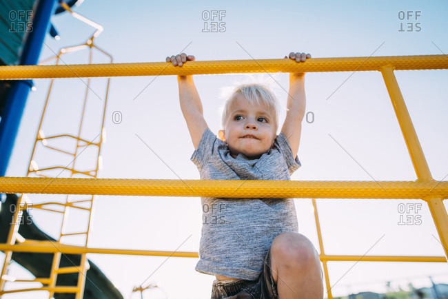 Low angle view of boy climbing on jungle gym against sky at park