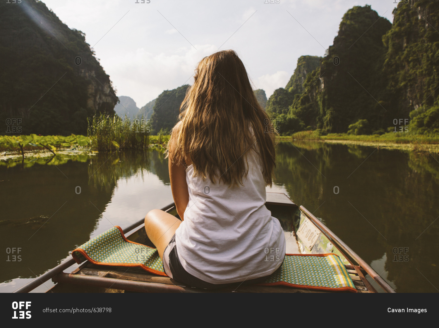 Rear view of woman looking at view while traveling in boat on river